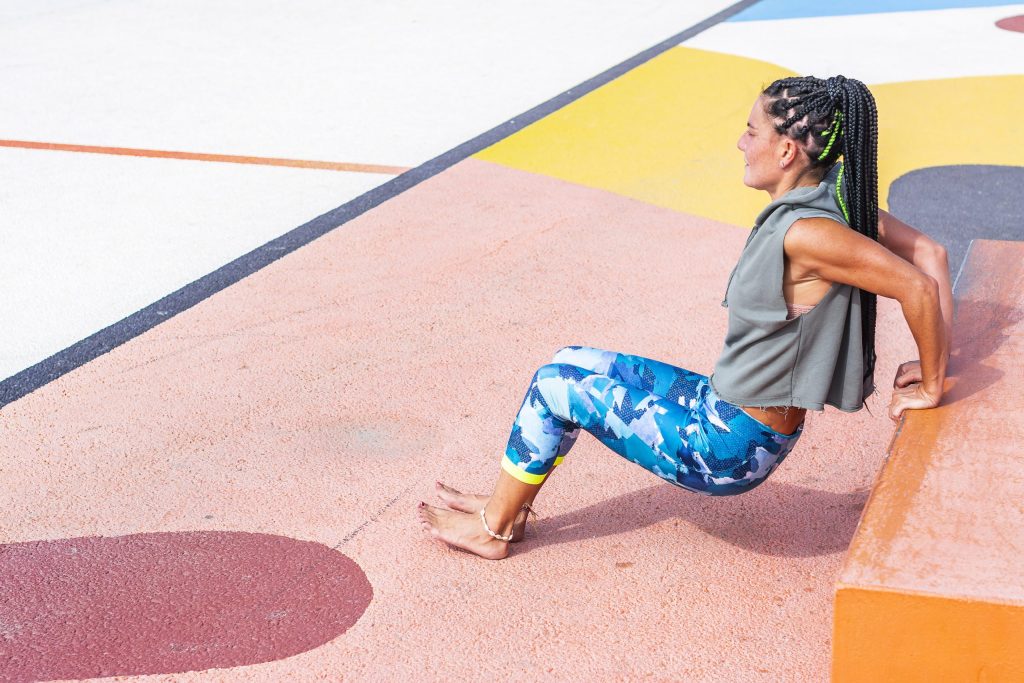 A woman doing dips in a park.